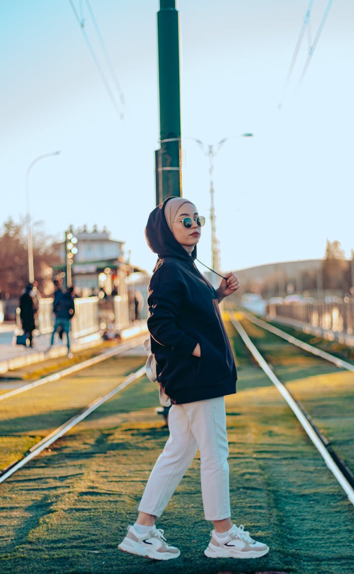 Services A fashionable woman in sunglasses walking along railroad tracks in Gaziantep, Turkey during the day.