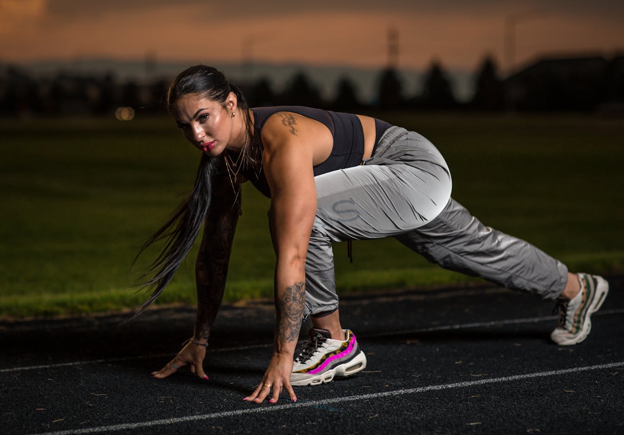 About Female athlete in starting position on track at dusk, showcasing determination.